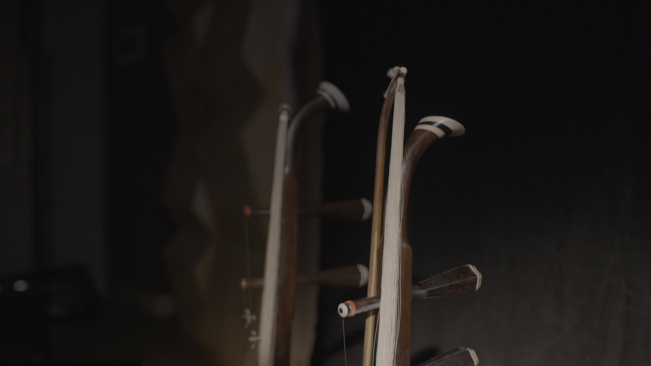 Erhu neck and bow detail against a dark studio backdrop